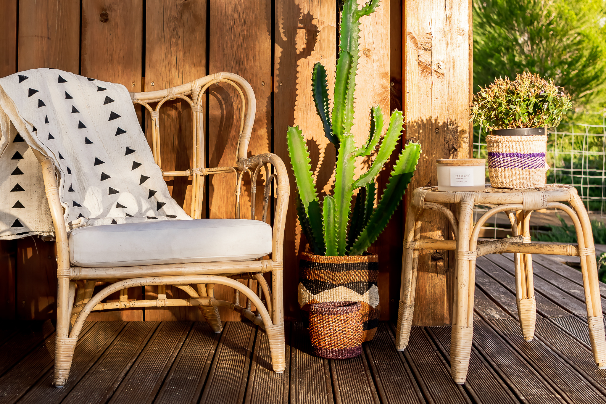 espaço exterior com duas cadeiras do estilo mediterrâneo com mantas e plantas