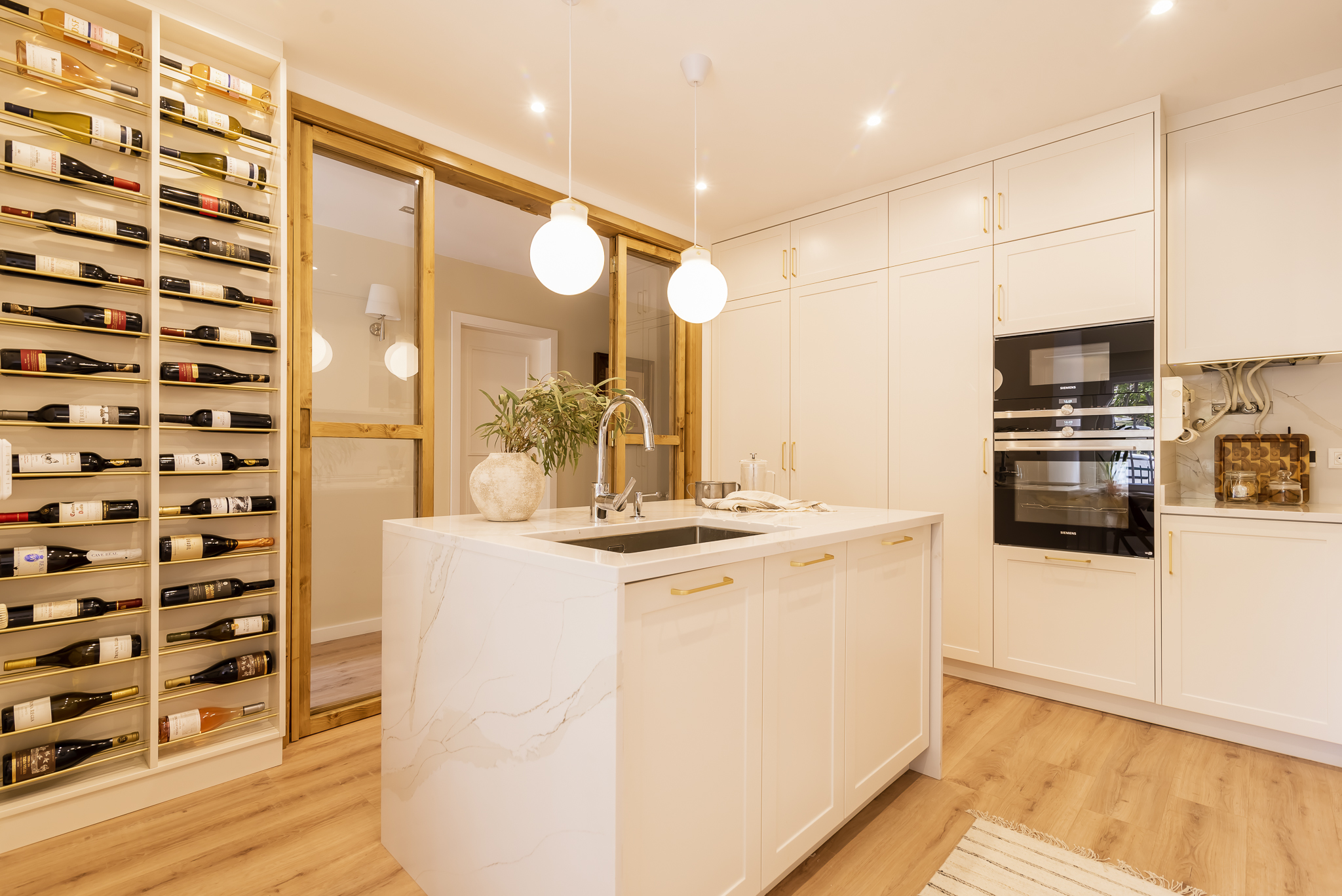 Design de interiores - Cozinha moderna com armários tipo shaker e ilha, acabamentos brancos e madeira