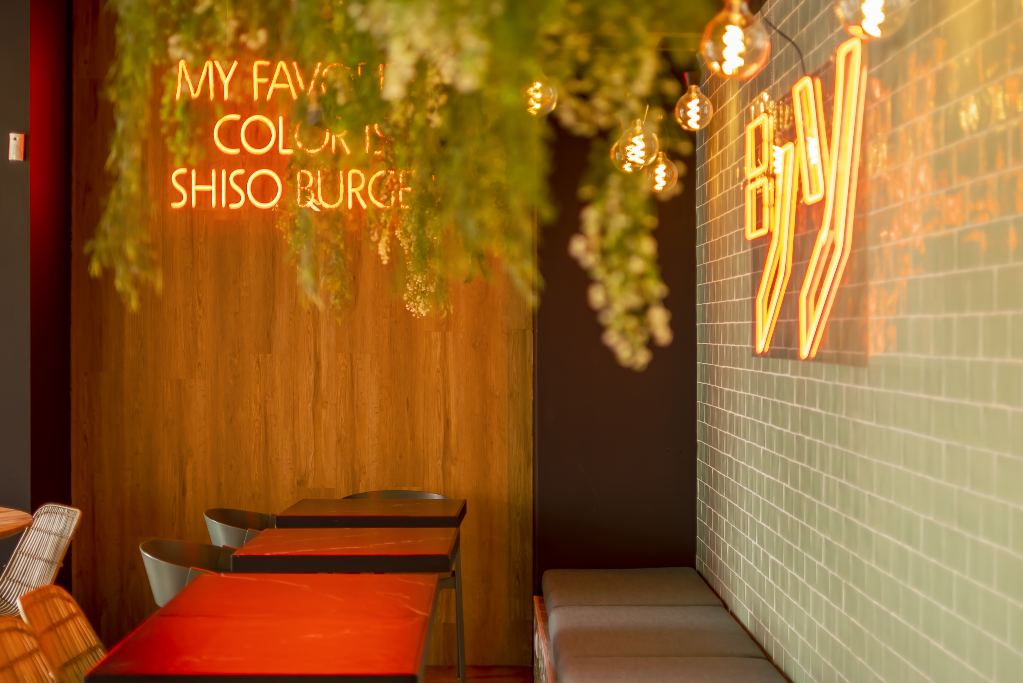 Decoração de interiores de um restaurante com estilo eclético, mas contemporal com neons laranjas e paredes com azulejos e detalhes em bambú; paleta de cores vibrante; hamburgueria gourment; Shiso Burger.
