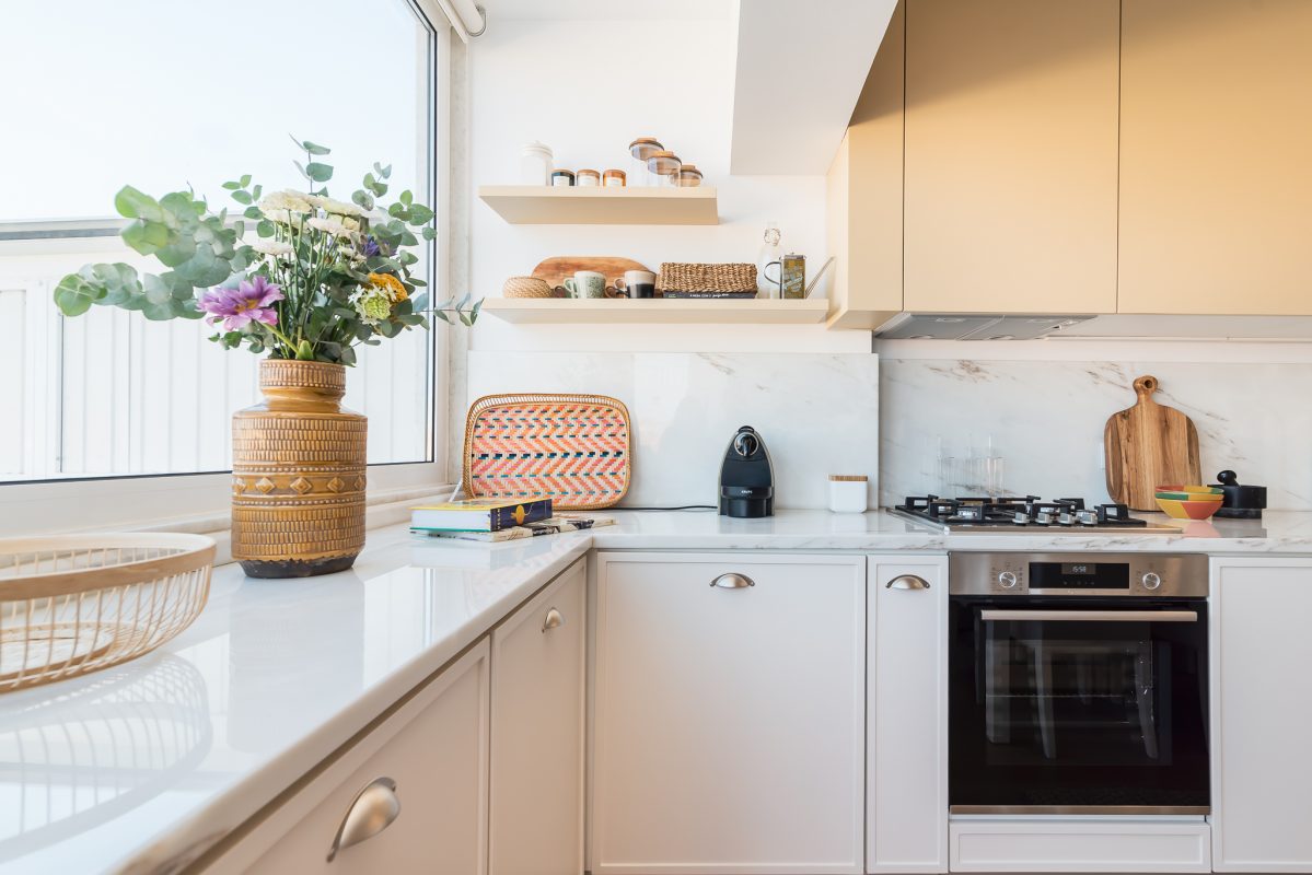 Reabilitação de cozinha minimalista em open space com armários brancos e amarelos