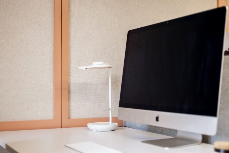 Escritório pequeno inserido em co-working com soluções modernas fechada de armazenamento; tons rosa e bege; cadeiras ergonómicas