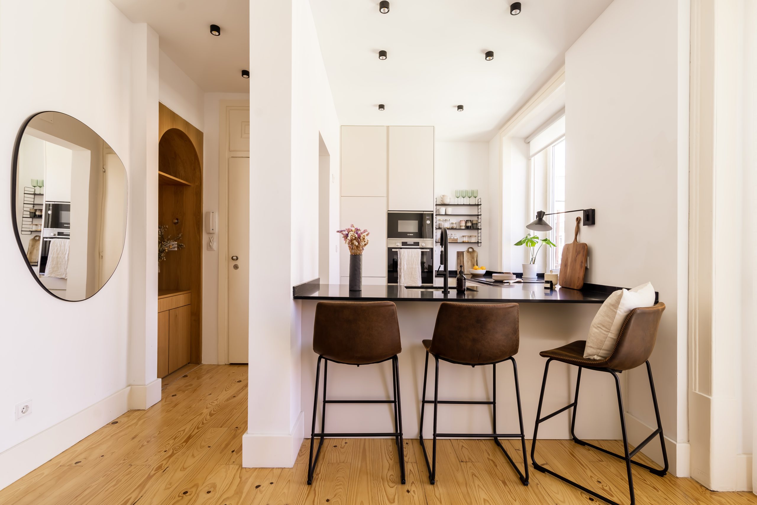 cozinha moderna e minimalista com cadeirões altos e espelho irregular