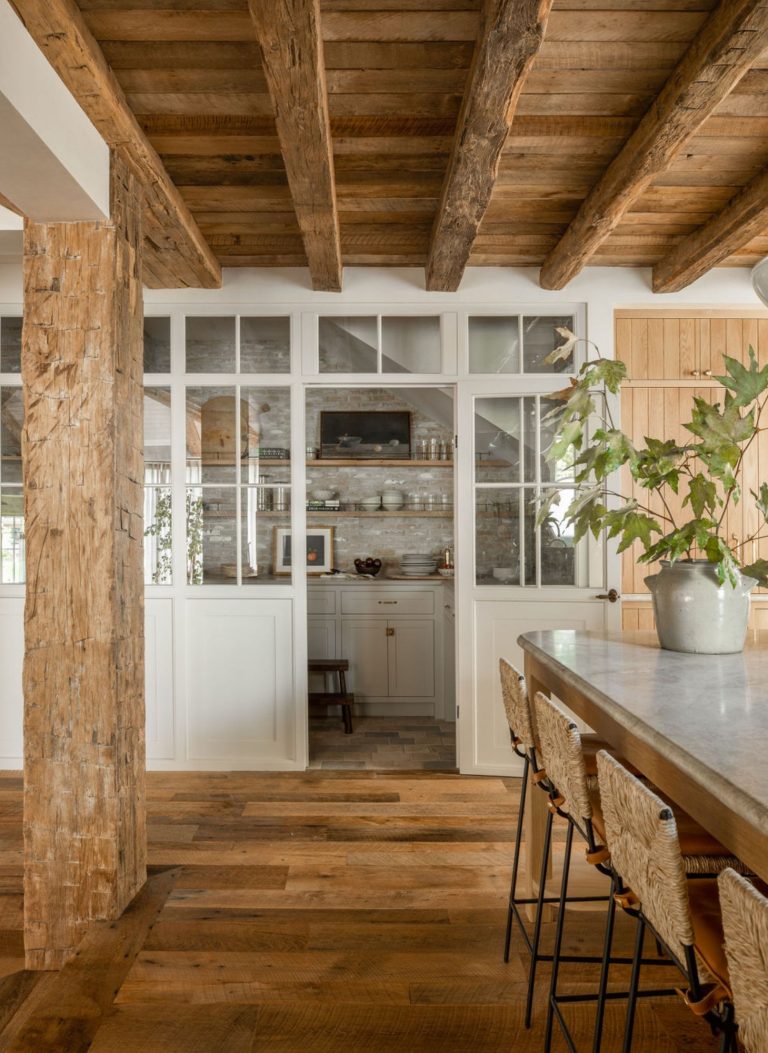 cozinha com ilha em madeira e tons brancos, bancos em madeira; porta/ virtrine para dispensa em tons brancos