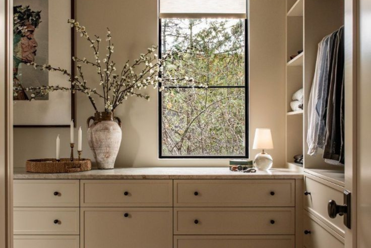 Closet feito por medida, com roupa arrumada em prateleiras e cabides, num ambiente sereno com luz natural.