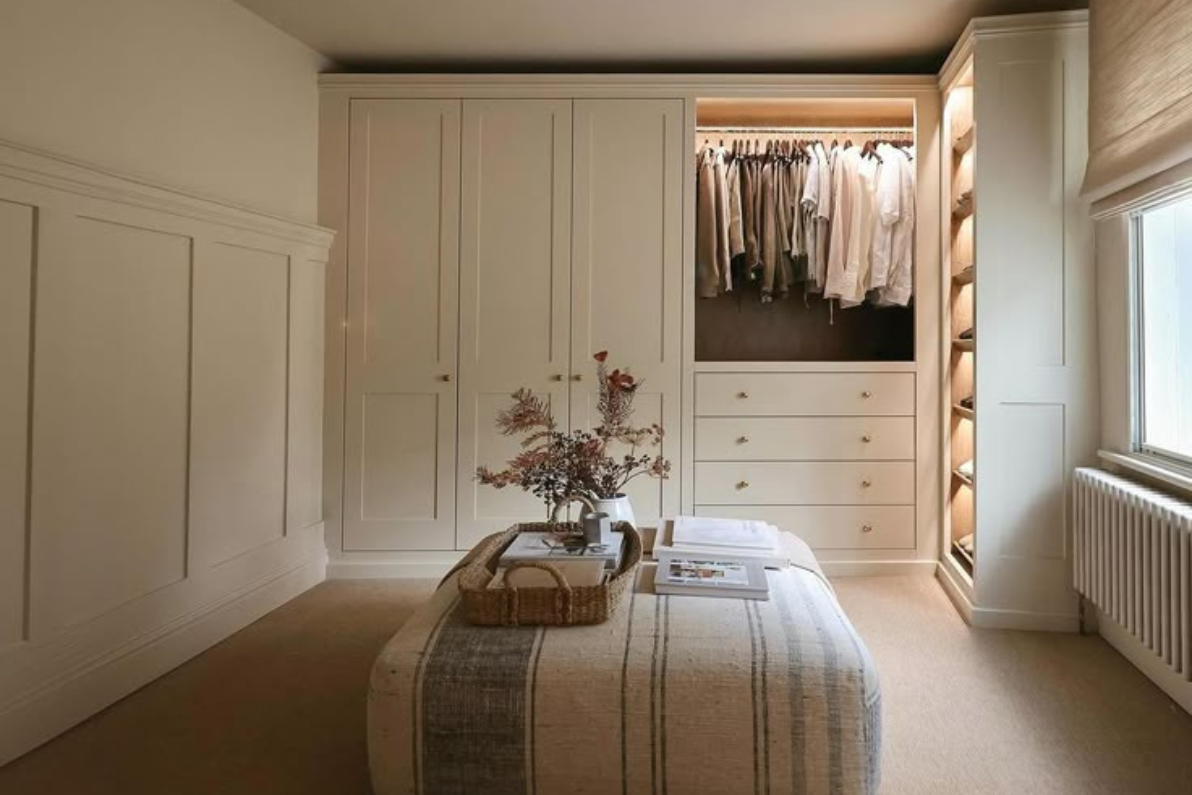 Quarto feminino com roupeiro alto em tom salmão e cómoda vintage com espelho.