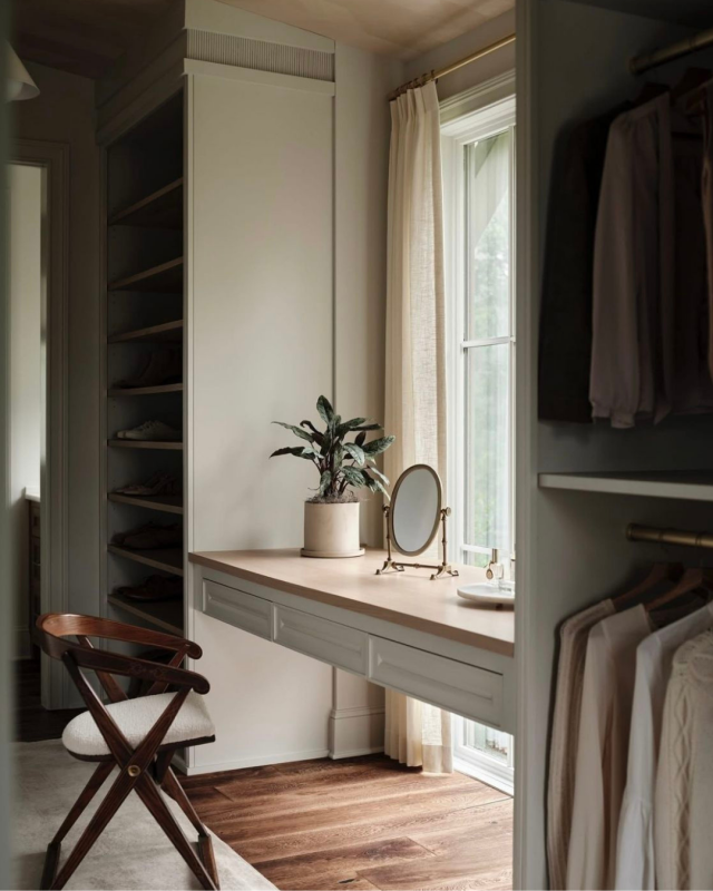 Closet moderno com roupa em cabides, sapatos em prateleiras e toucador junto à janela.