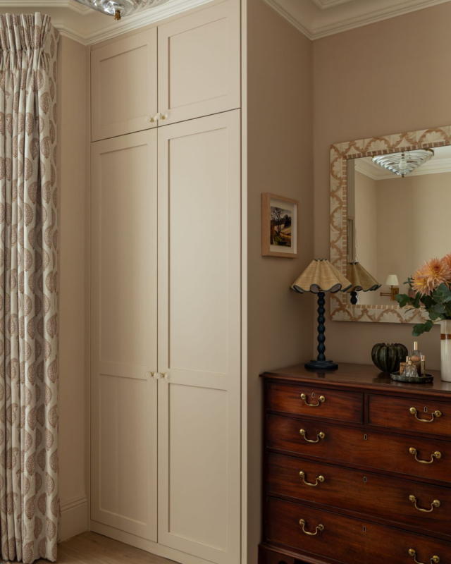 Quarto feminino com roupeiro alto em tom salmão e cómoda vintage com espelho.