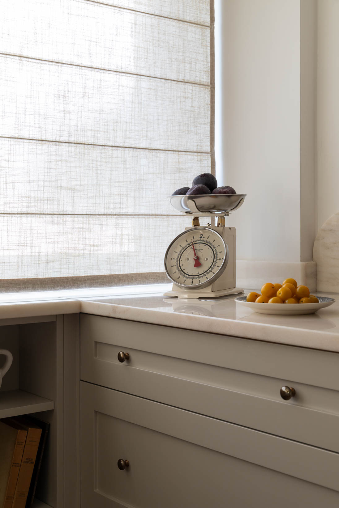 Detalhe da cozinha com armários lacados e estores em linho natural